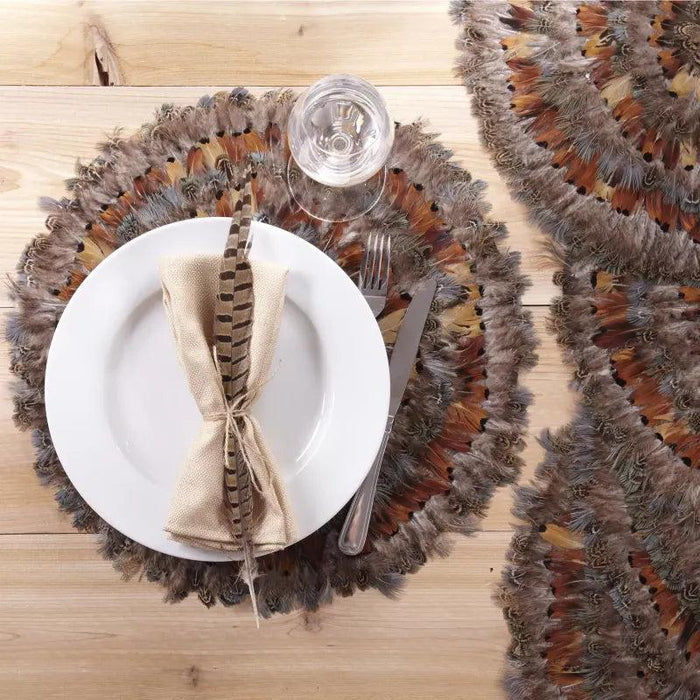Round 16-inch placemat made of layered, iridescent brown, grey, and green pheasant feathers on a wooden table.
