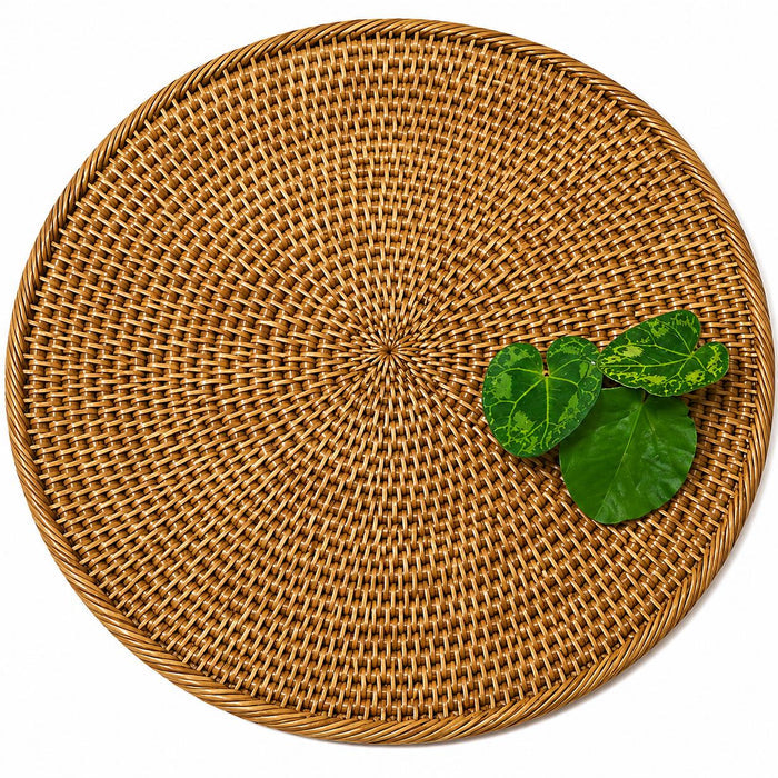 14-inch round handwoven Burmese rattan placemat in a natural tan finish with green decorative leaves.