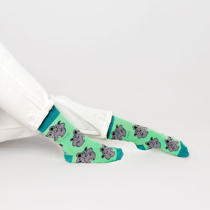 sitting model with feet outstretched wearing green koala socks