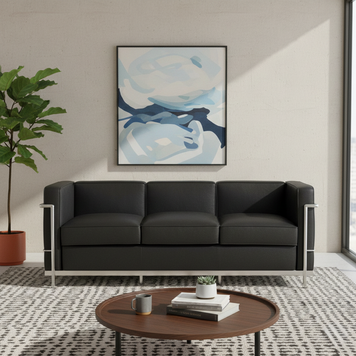 Modern living room with a black sofa, round wooden coffee table, and abstract art on the wall.