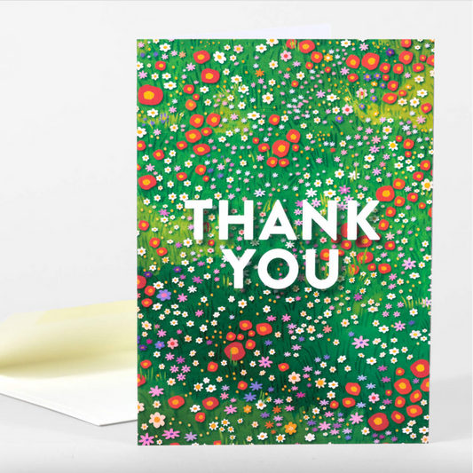 Card with a meadow of multicolored wildflowers and white text on top that says "Thank You"