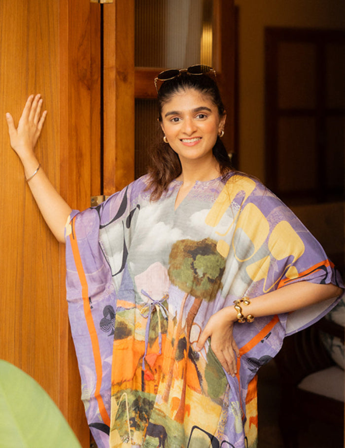 Woman wearing a colorful dress with artistic design, standing indoors.