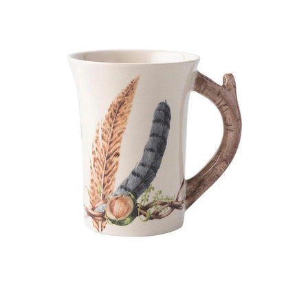 Juliska Forest Walk ceramic mug featuring feather patterns and a rustic branch-shaped handle on a cream background.