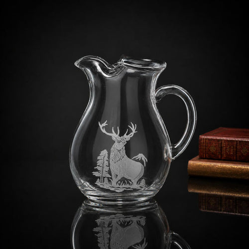 84 oz clear crystal pitcher featuring a multi-layered hand-carved elk and forest design against a dark background.
