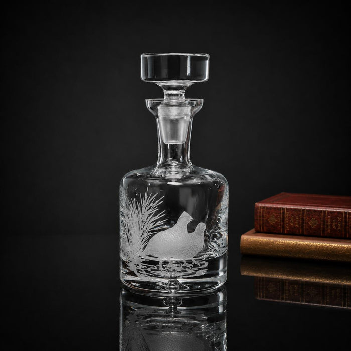 Clear crystal decanter with a multi-layer hand-carved Bob White Quail design and glass stopper on a reflective surface.