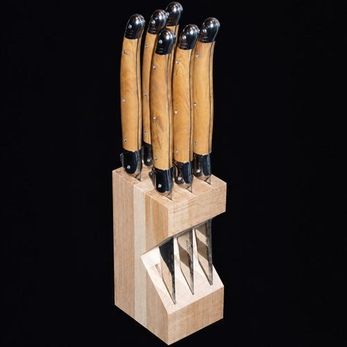 Set of six Laguiole steak knives with olive wood handles and stainless steel bolsters in a beechwood block.