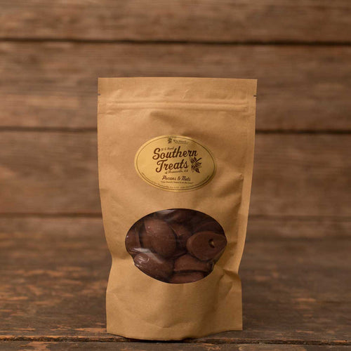 Milk chocolate-covered pecans in a brown stand-up pouch with a Southern Treats label against a rustic wood background.