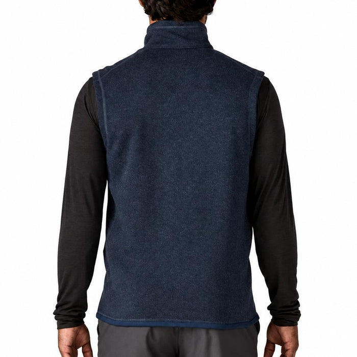 Back view of a navy blue Patagonia Better Sweater fleece vest with a stand-up collar worn over a black long-sleeve shirt.