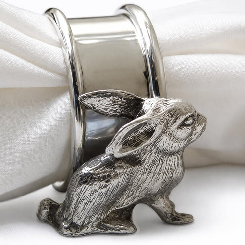 Artisanal pewter napkin ring featuring a detailed sculpted rabbit motif holding a white fabric napkin.