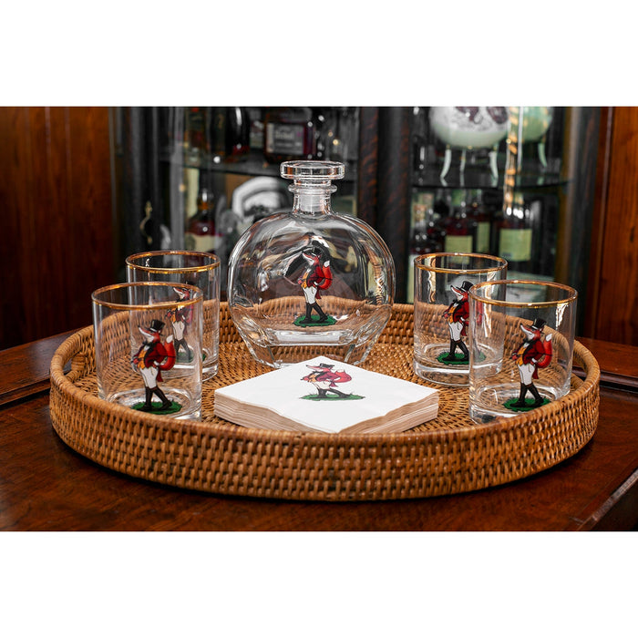Four Snooty Fox double old-fashioned glasses with gold rims and matching decanter on a round woven rattan tray.