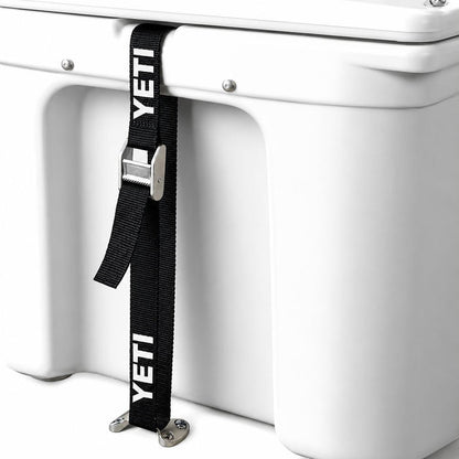 Black YETI tie-down strap with metal buckle secured to a white cooler and a low-profile stainless steel deck plate.
